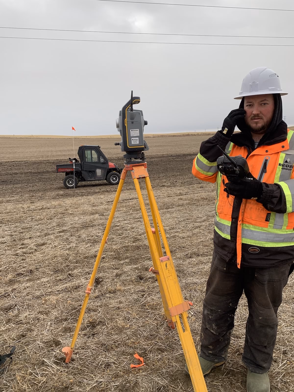 TSM surveyor setting up equipment beside a survey vehicle in a snow-covered field